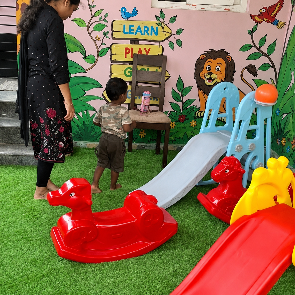 Play zone with slide and ride-on toys at Cambridge Montessori Shalimar Bagh